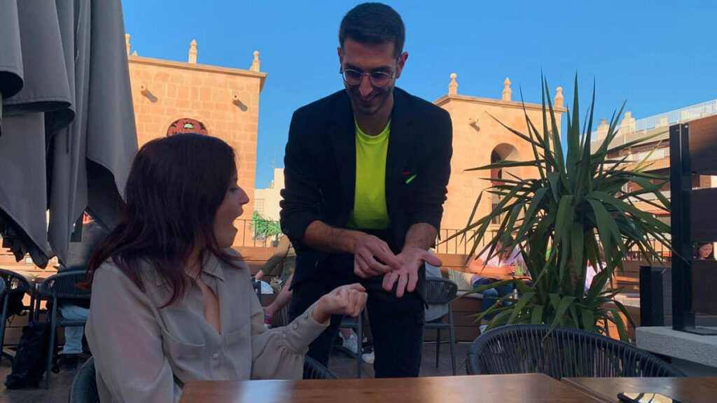 El mago ilusionista Mino haciendo magia para restaurantes mientras los espectadores reaccionan embelesados.